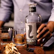 LEGENT bourbon bottle held in hand with a glass containing ice and drink in the foreground, set in a bar environment